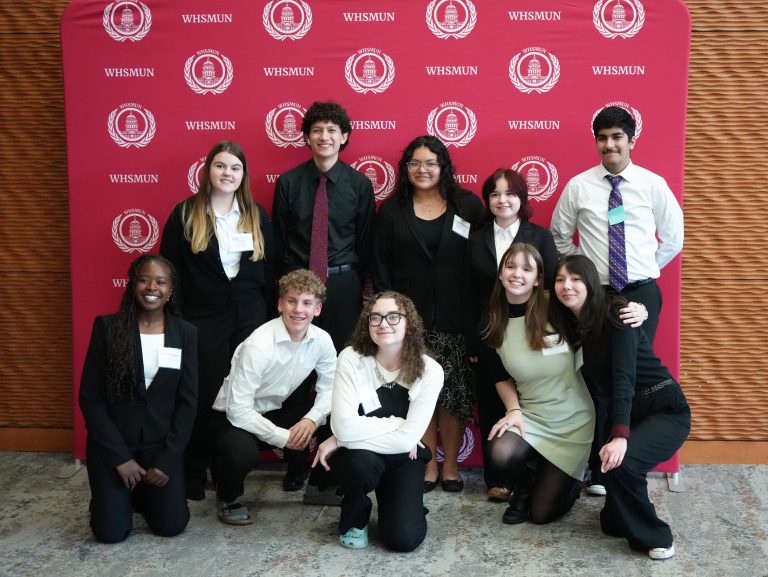 Students pose in front of a WHSMUN banner
