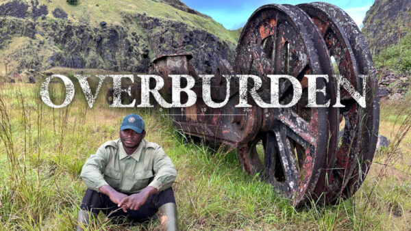 Film Cover of a man sitting in front of a big rusty wheel surrounded by nature